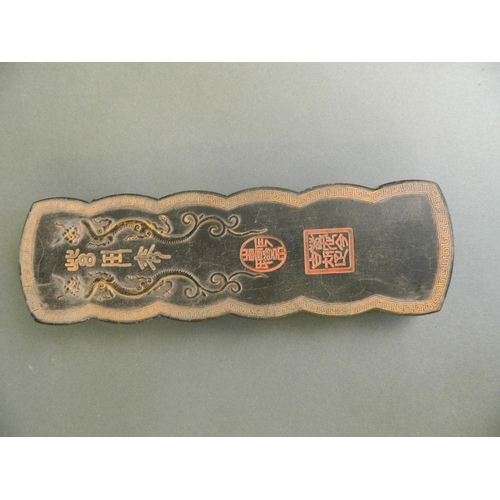 90 - A Chinese black ground ink stone with twin dragon decoration and character inscription, boxed, 10