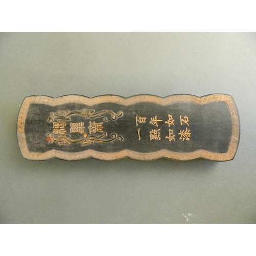 90 - A Chinese black ground ink stone with twin dragon decoration and character inscription, boxed, 10