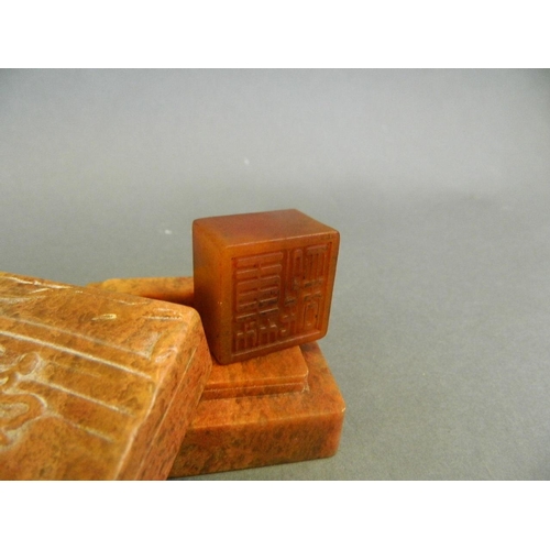 91 - A Chinese mottled orange soapstone box opening to reveal an amber soapstone seal, the lid with carve... 