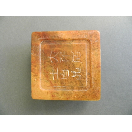 91 - A Chinese mottled orange soapstone box opening to reveal an amber soapstone seal, the lid with carve... 