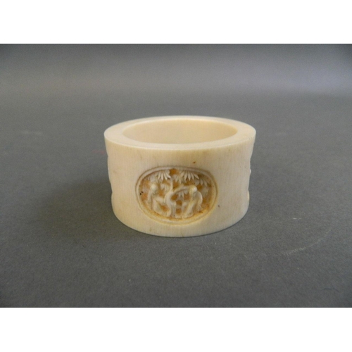 147 - A finely carved Cantonese ivory napkin ring with decorative panels depicting figures under cypress t... 