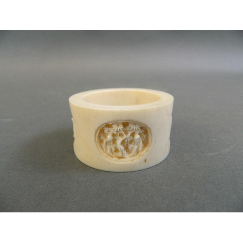 147 - A finely carved Cantonese ivory napkin ring with decorative panels depicting figures under cypress t... 