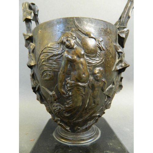 165 - A C19th twin handled bronze urn with relief classical decoration, mounted on a hardstone base, 7