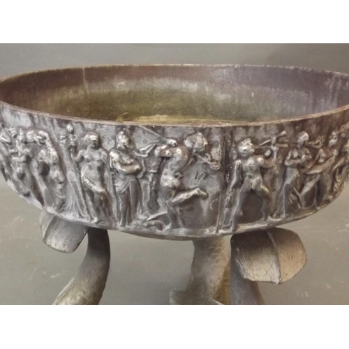 181 - A lead planter, the rim embossed with Bacchanalia figures, on three cast iron stylised dolphin suppo... 