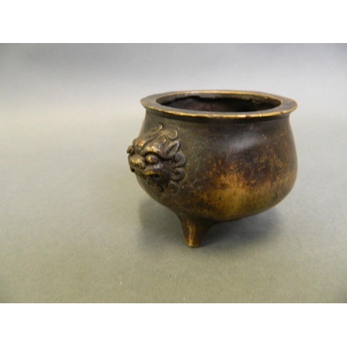 215 - A Chinese bronze censer with twin mask handles, on tripod feet, 4 character mark to base, 2½