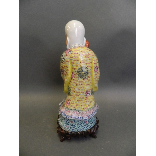 240 - A Chinese polychrome enamelled porcelain figure of Yue Lao, mounted on a carved hardwood base, 10