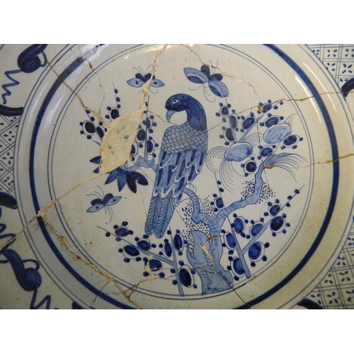 265 - An early C18th Delft blue and white charger decorated with an exotic bird and butterflies, 14