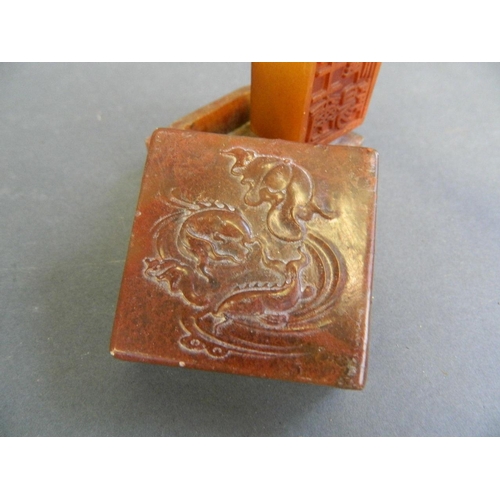 29 - A Chinese red soapstone box with engraved decoration of carp to lid, and amber soapstone seal within... 