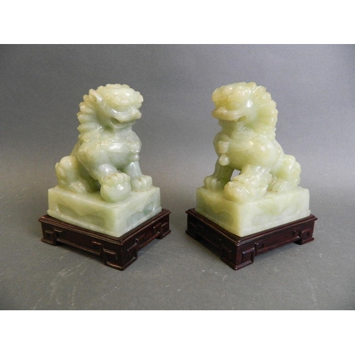 350R - A pair of celadon green hardstone ornaments carved in the form of kylin, on a pair of matched carved... 