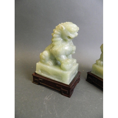 350R - A pair of celadon green hardstone ornaments carved in the form of kylin, on a pair of matched carved... 