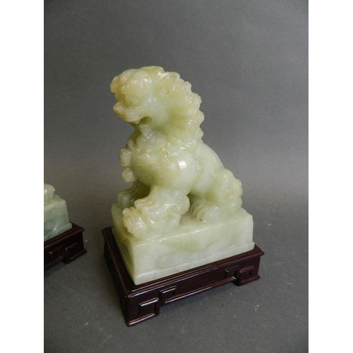 350R - A pair of celadon green hardstone ornaments carved in the form of kylin, on a pair of matched carved... 