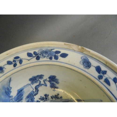 351 - A Chinese blue and white porcelain bowl decorated with fishermen in a boat on a lake, on three kylin... 