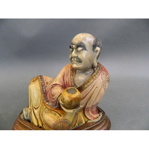 412 - A Chinese soapstone figure of a reclining immortal, mounted on a hardwood stand, 5½