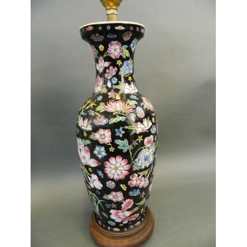 416 - A Chinese porcelain vase decorated with flowers in bright enamels on a black ground, converted to a ... 