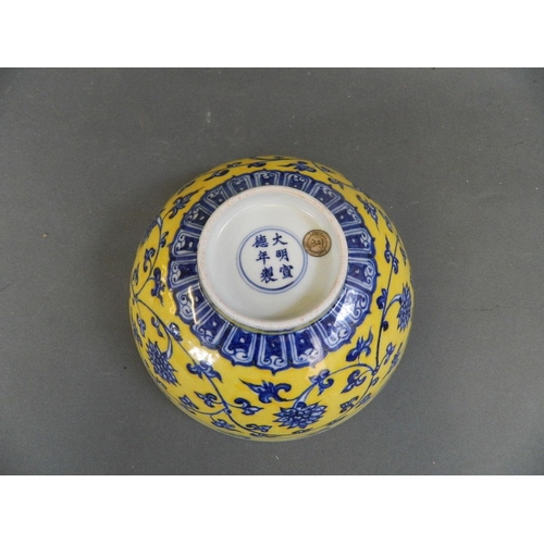 448 - A Chinese yellow ground porcelain bowl with blue and white scrolling lotus flower decoration, 6 char... 