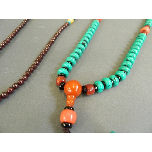 526 - A string of turquoise style beads with amber style feature beads, together with a string of garnet s... 