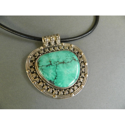 528 - A Tibetan turquoise stone pendant in a white metal mount, 2½