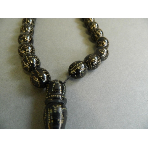 534 - A string of Middle Eastern black lacquer beads with copper inset decoration, 23