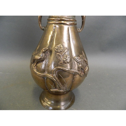 60 - An Oriental bronze ribbed vase with twin elephant mask handles and applied relief decoration of bird... 