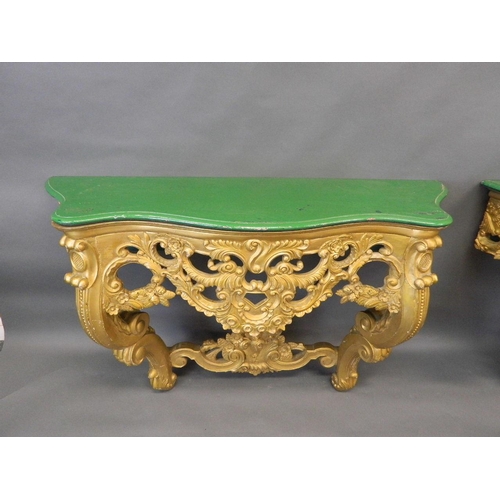 714 - A pair of giltwood console tables with serpentine shaped and carved painted tops, 55