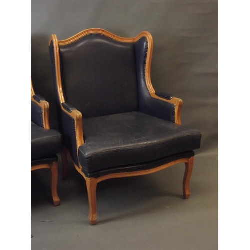 777 - A pair of French style beech wood framed winged armchairs with leather cushions and upholstery