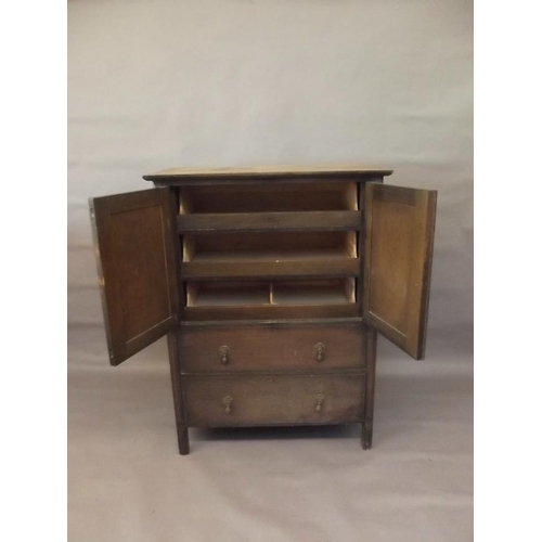 784 - A 1930s oak gentleman's press cupboard with two cupboards fitted with slides over drawers, raised on... 