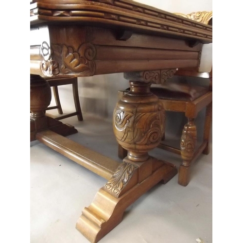 807 - A good golden oak draw leaf dining table with carved frieze, raised on carved bulbous end supports u... 