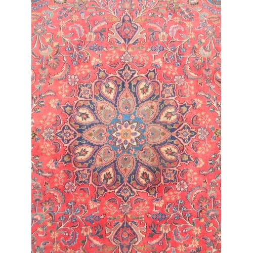 863 - A large antique red ground Persian Kashan carpet with medallion design on a blue field within a flor... 