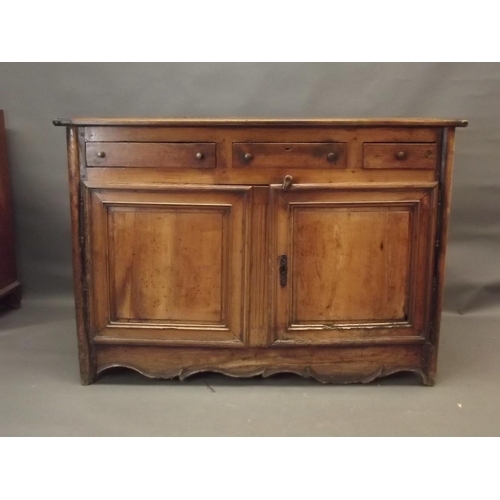 864 - An early C20th French fruitwood buffet with three drawers over two panelled doors, with a shaped car... 