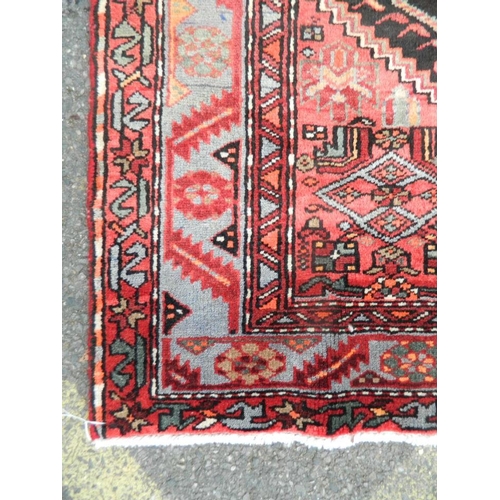 869 - A hand woven Persian Hamadan Luri carpet with all over design on a red field, 55