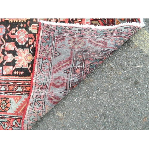 869 - A hand woven Persian Hamadan Luri carpet with all over design on a red field, 55