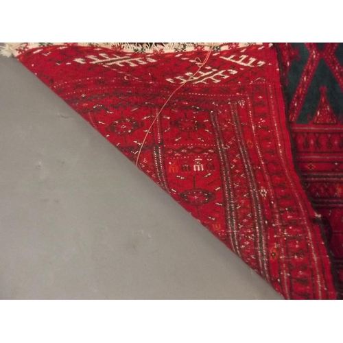 876 - An Afghan carpet with geometric design on a red ground, 36½