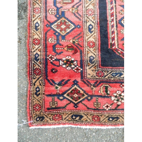 879 - A Persian Hamadan Luri carpet with bespoke medallion design on a red and ebony field, 52