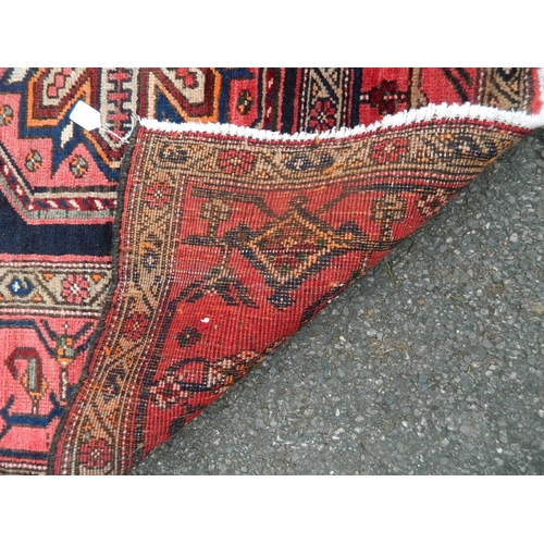 879 - A Persian Hamadan Luri carpet with bespoke medallion design on a red and ebony field, 52