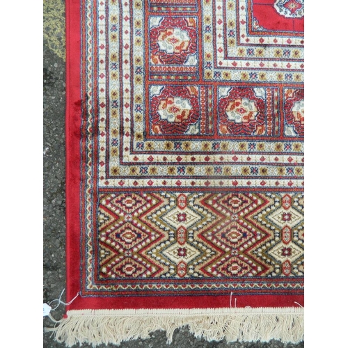 882 - A large red ground Kashmir carpet with ivory Bukhara design, 108