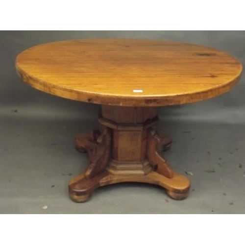 891 - A pine circular topped dining table, raised on an octagonal column and shaped platform with bun feet... 