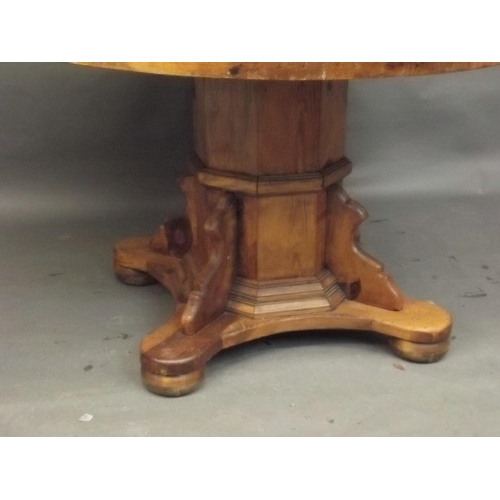 891 - A pine circular topped dining table, raised on an octagonal column and shaped platform with bun feet... 