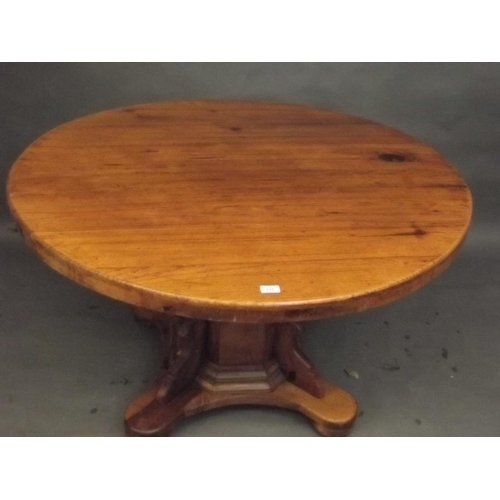 891 - A pine circular topped dining table, raised on an octagonal column and shaped platform with bun feet... 