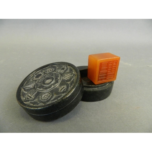 139 - A Chinese green hardstone cylinder shaped box containing an amber soapstone seal with carved decorat... 