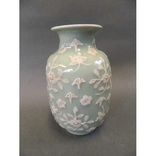 143 - A Chinese celadon glazed porcelain vase with relief carved white enamel floral decoration, 4 charact... 