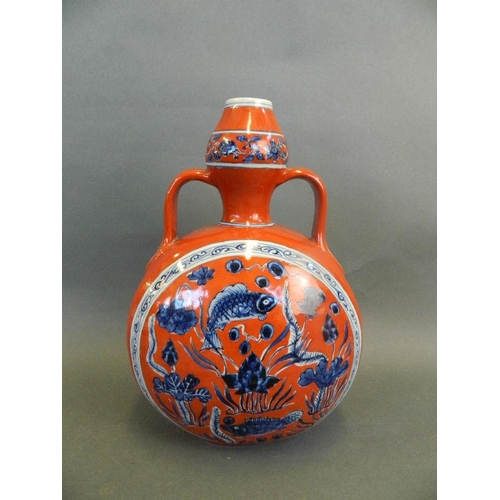 164 - A Chinese red ground twin handled moon flask with blue and white decoration of carp in a lotus pond,... 