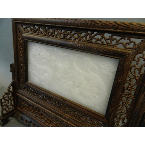 212 - A Chinese white jade and hardwood table screen with carved decoration of twin dragons chasing the fl... 