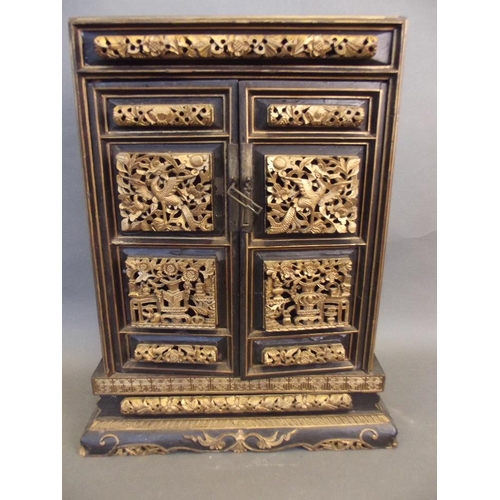 475 - A Chinese black lacquer and gilt table top shrine cabinet, the doors decorated with pierced and carv... 