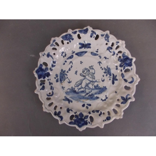 476 - An Italian blue and white Majolica plate decorated with a cherub within a pierced petal shaped rim, ... 