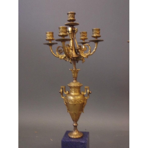 54 - A pair of four branch ormolu candelabra, the bodies in the form of classical urns, mounted on lapis ... 