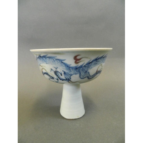 65 - A Chinese porcelain stem bowl decorated in blue and red with a dragon amongst clouds, 3½