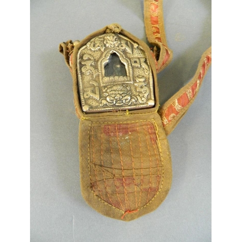 83 - A Sino-Tibetan white metal travelling shrine with embossed decoration, in an embroidered fabric carr... 