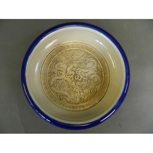 18 - A Chinese blue glazed porcelain bowl with raised decoration to the interior of two dragons encirclin... 