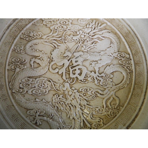 18 - A Chinese blue glazed porcelain bowl with raised decoration to the interior of two dragons encirclin... 