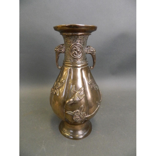 50M - An Oriental bronze ribbed vase with twin elephant mask handles and applied relief decoration of bird... 